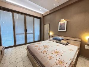 a bedroom with a large bed and large windows at Manav Farmhouse in Olpād