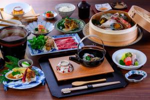 a wooden table with plates of food and chopsticks at Okamotoya in Beppu