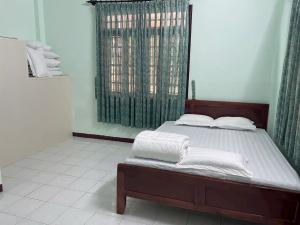 a bedroom with a bed with white sheets and a window at maison Ty Homestay in Phan Thiet