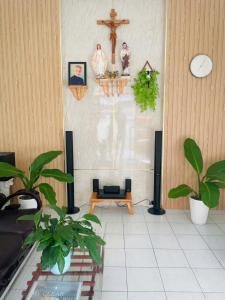 a living room with plants and a cross on the wall at maison Ty Homestay in Phan Thiet