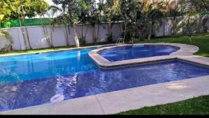 a blue swimming pool in a yard with a fence at VILLA REAL lll YAUTEPEC in Yautepec de Zaragoza