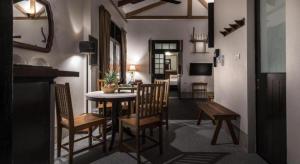 a living room with a dining room table and chairs at Uthai Heritage Hotel in Ban Nong Nam Khan