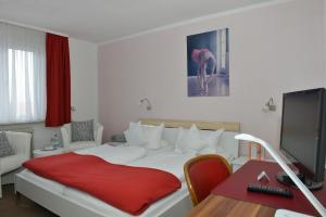 a bedroom with a bed with a red blanket on it at Hotel Moorbadstuben in Bad Buchau