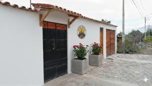 a white building with a black door and two potted plants at Anta lodge in Huaraz