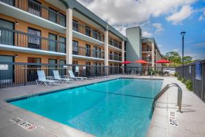 a pool in front of a hotel with chairs and umbrellas at Quality Inn West Fort Worth in Fort Worth