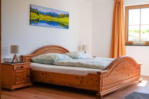 a bedroom with a bed with a wooden frame and a window at Ferienwohnung auf dem Stroblhof in Polling +13 photos