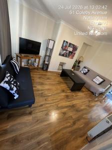 a living room with a black couch and a wooden floor at CosyColeby in Nottingham