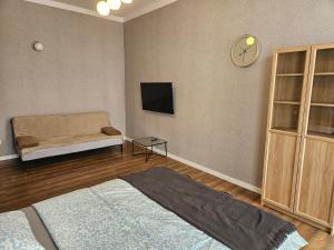 a living room with a bed and a clock on the wall at Blu Apartament in Strzelno