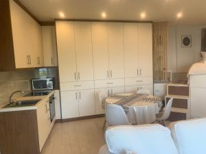 a kitchen with white cabinets and a table and chairs at Amfiteatriko Studio Sea View Oropos Attiki in Kalamos