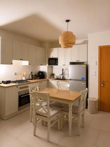 a kitchen with a wooden table and chairs at Marassi- Faya Residence in El Alamein