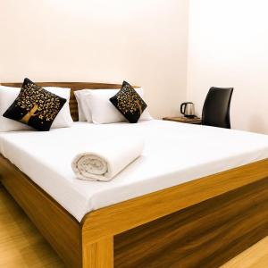 a bed with white sheets and black pillows on it at Aishwaryam Hotels & service Apartment in Madurai