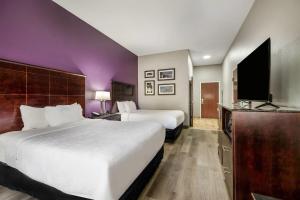 a hotel room with two beds and a flat screen tv at La Quinta Inn & Suites by Wyndham Louisville East in Louisville
