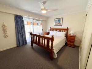 a bedroom with a wooden bed and a window at Ocean Shores Apartment 13 in South West Rocks +14 photos