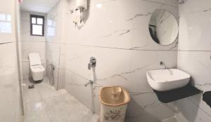 a white bathroom with a sink and a toilet at Hotel Sunrise in Ahmedabad