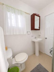 a white bathroom with a toilet and a sink at Casa brisa del caribe in Juan López