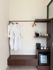 a white coat hanging on a wall next to a tv at Samphia Homestay in Nguyệt Hòa
