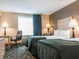 a hotel room with two beds and a desk and a chair at Quality Inn Geneseo in Geneseo +57 photos