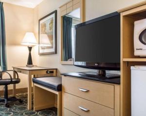 a hotel room with a flat screen tv and a desk at Quality Inn Geneseo in Geneseo