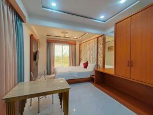a hotel room with a bed and a desk and a tv at Lions Hotel Adidev in Badlapur