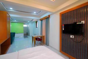 a room with a tv on a wall with a table at Lions Hotel Adidev in Badlapur
