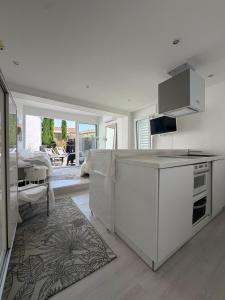 a kitchen with white cabinets and a living room at Little White House in Anglet