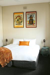 a bedroom with a large white bed with two pictures on the wall at The Kyneton Hotel in Kyneton