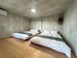 two beds in a room with wooden floors at Deer Path Nara in Nara