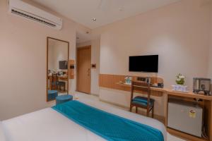 ein Hotelzimmer mit Bett und Schreibtisch mit Fernseher in der Unterkunft Hotel 7 skye in Surat