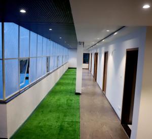 an empty corridor with green flooring in an office building at Hotel Ellora Pride in Ellora