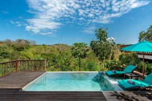a swimming pool with chairs and an umbrella at Emana Aruna in Toyapakeh