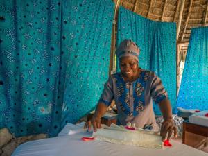 a woman cutting a cake on top of a bed at Zoi Retreat Hotel Zanzibar in Matemwe