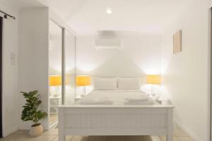 a white bedroom with a bed and a mirror at Elegant & Cozy Private Studio in Wellington Point