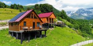a wooden house on a hill with mountains in the background at SkyGona Alpine Retreat in Ghebi