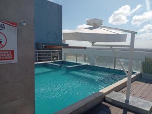 a swimming pool with an umbrella and a swimming poolvisor at JG Hotel in Santa Cruz de la Sierra
