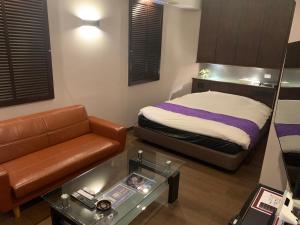a small bedroom with a bed and a couch at Rplus八千代 in Chiba