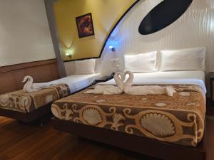 two beds in a hotel room with swans on them at Kohinoor Hotels in Erode +34 photos