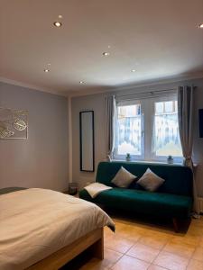 a bedroom with a green couch in front of a window at Ela´s Alstadtliebe in Wertheim