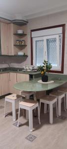 a kitchen with a green table and benches and a window at Casa dos avós in Redondela