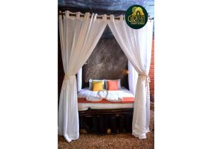 a canopy bed with white curtains and colorful pillows at Giripura Resort - Kandy in Kandy +23 photos