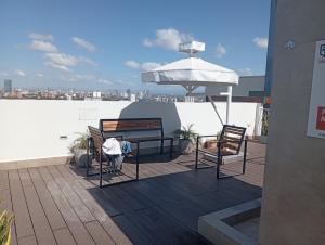 a patio with two benches and an umbrella on a roof at JG Hotel in Santa Cruz de la Sierra