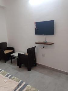 a room with two chairs and a tv on a wall at Hotel rose palace in Dehradun