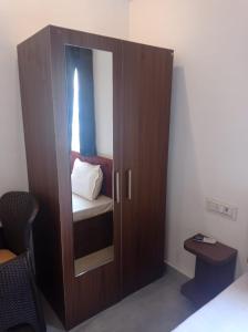 a wooden cabinet with a mirror in a bedroom at Hotel rose palace in Dehradun