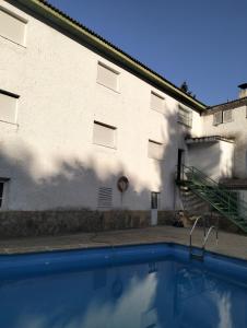 a building and a swimming pool in front of a building at Pensión Rural Arroyo la Teja in Arroyo Frio