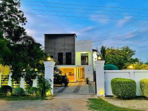 a house with a white fence and a driveway at Kiula Resort in Hambantota