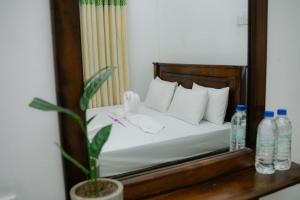 a bedroom with a bed with white sheets and water bottles at Kiula Resort in Hambantota