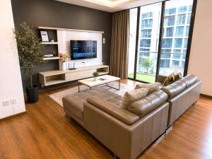 a living room with a leather couch and a television at Jazz Suite Vivacity Kuching in Kuching