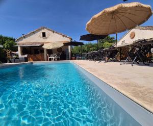 a swimming pool with an umbrella and chairs and tables at Le petit Riyade in Cambayrac