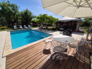a deck with a pool and a table and an umbrella at Le petit Riyade in Cambayrac +4 photos