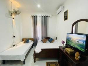 a room with two beds and a flat screen tv at Hotel Kandy Village Inn in Kandy
