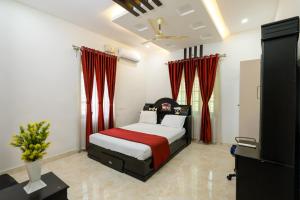 a bedroom with a bed with red curtains and a television at Heaven Stay in Varkala